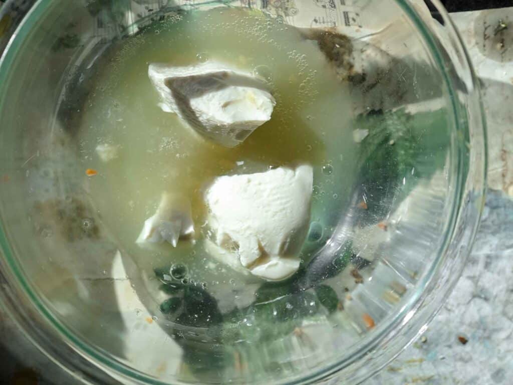 A glass bowl containing chunks of silken tofu submerged in aquafaba